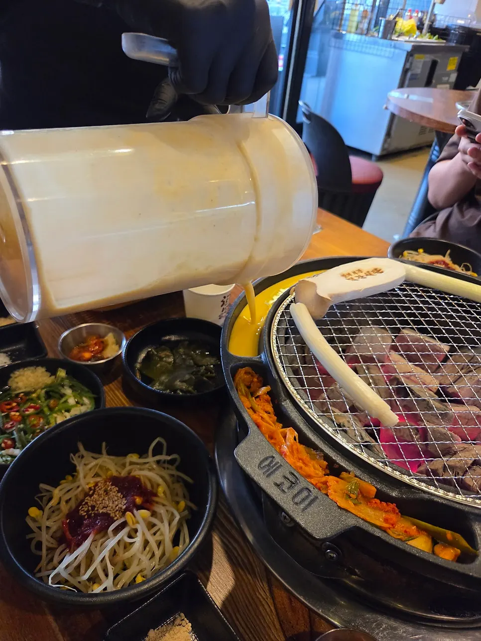 Stir-fried kimchi and sides along the edge of the charcoal grill