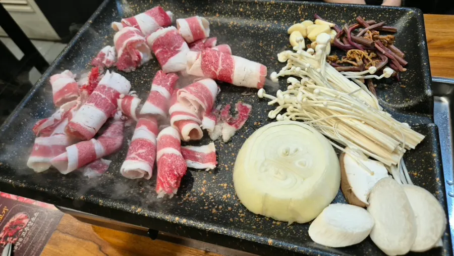 Potatoes, bracken fern, and kimchi grilling alongside the meat