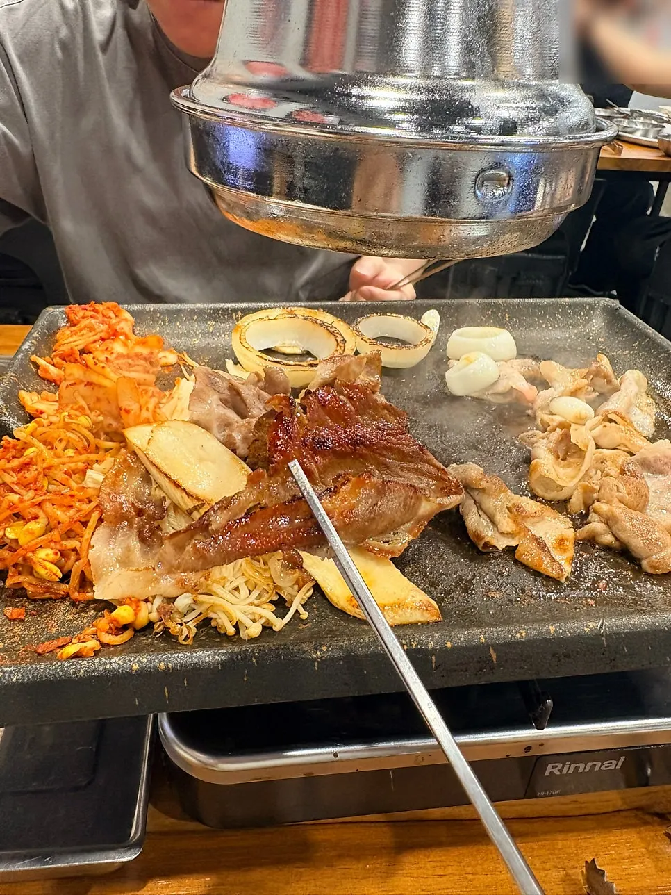 A full grill of shaved pork being cooked