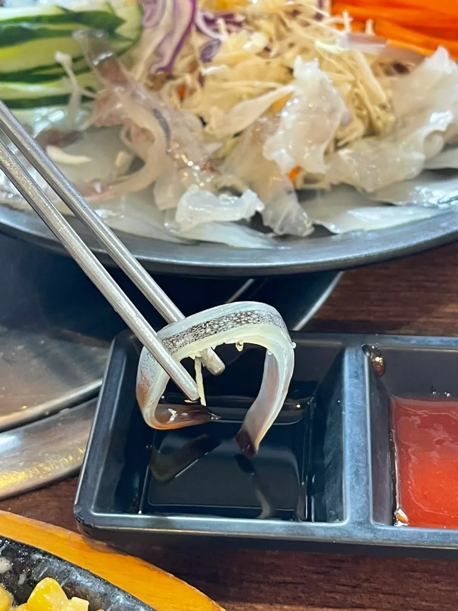 Thin slice of ojingeopo held with chopsticks