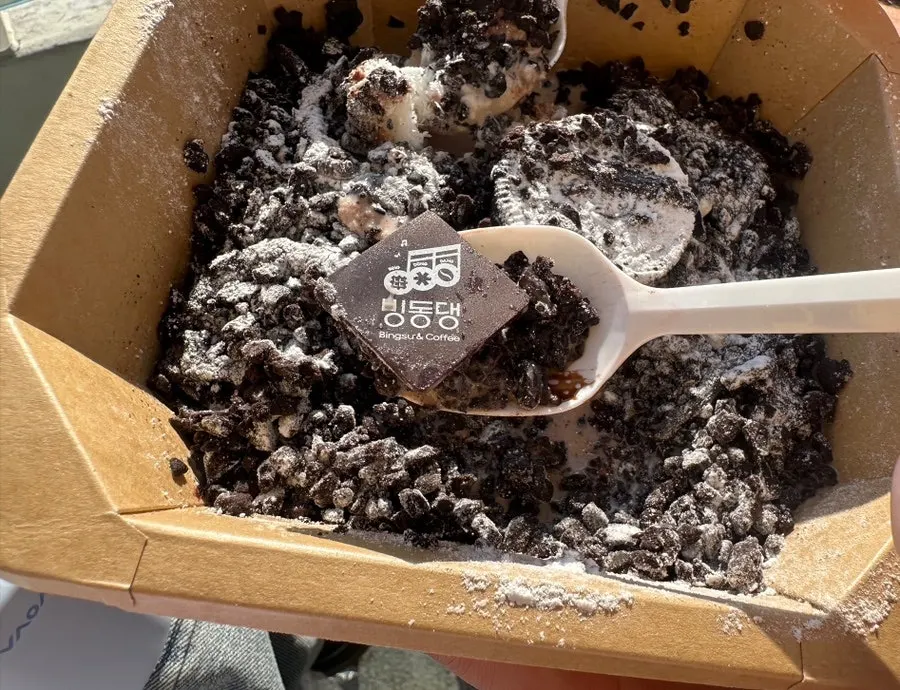A spoonful of choco oreo bingsu piled with crushed Oreo cookies