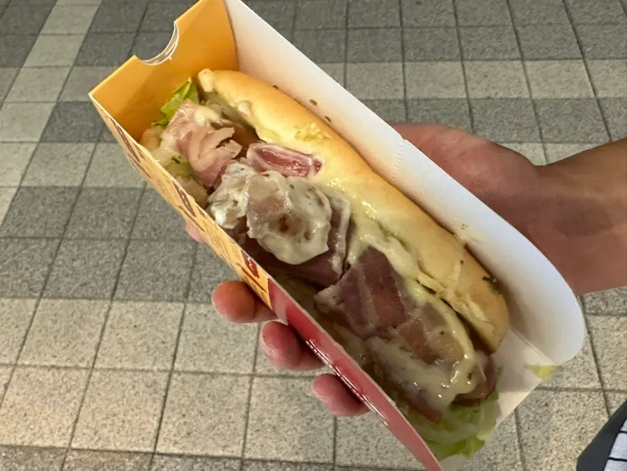 Cross-section of a bitten bacon white garlic hot dog