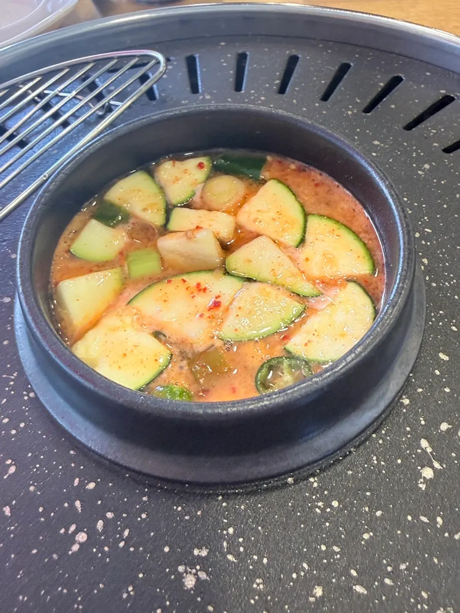 Doenjang broth at the center of the table with beef grilling