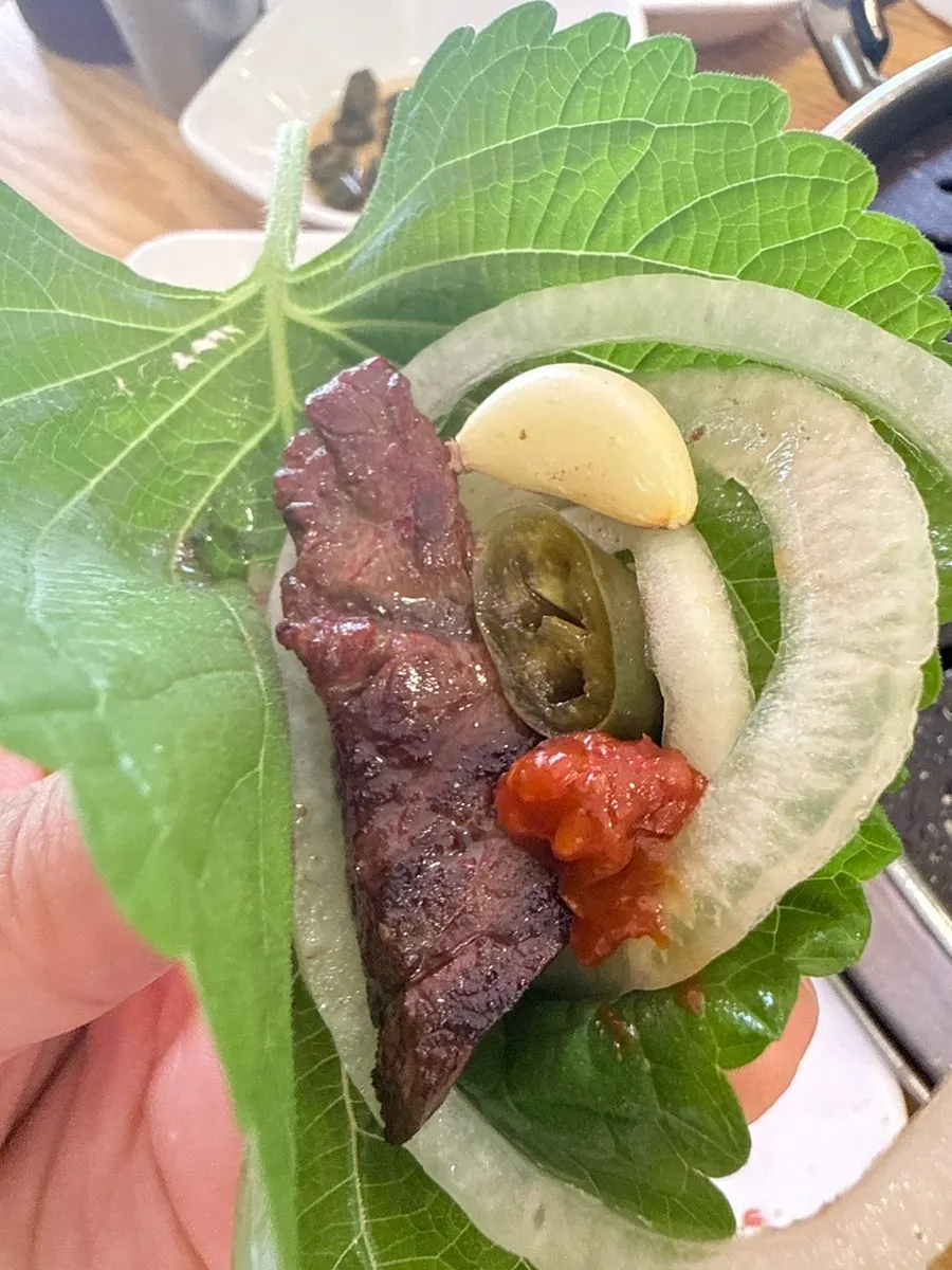 Beef wrap topped with kimchi and green onion salad