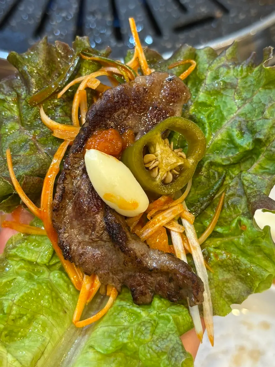 A bite of beef topped with ssamjang and garlic