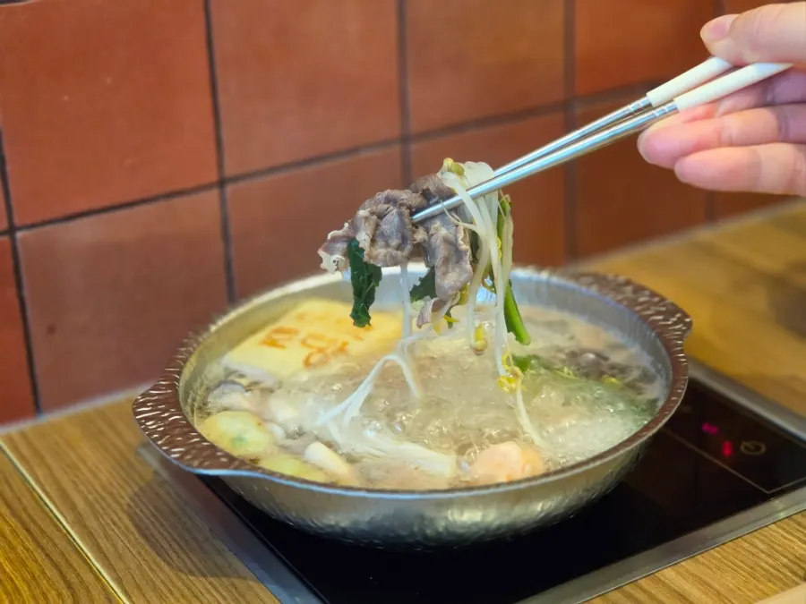Pot with glass noodles, rice cakes and dumpling toppings added