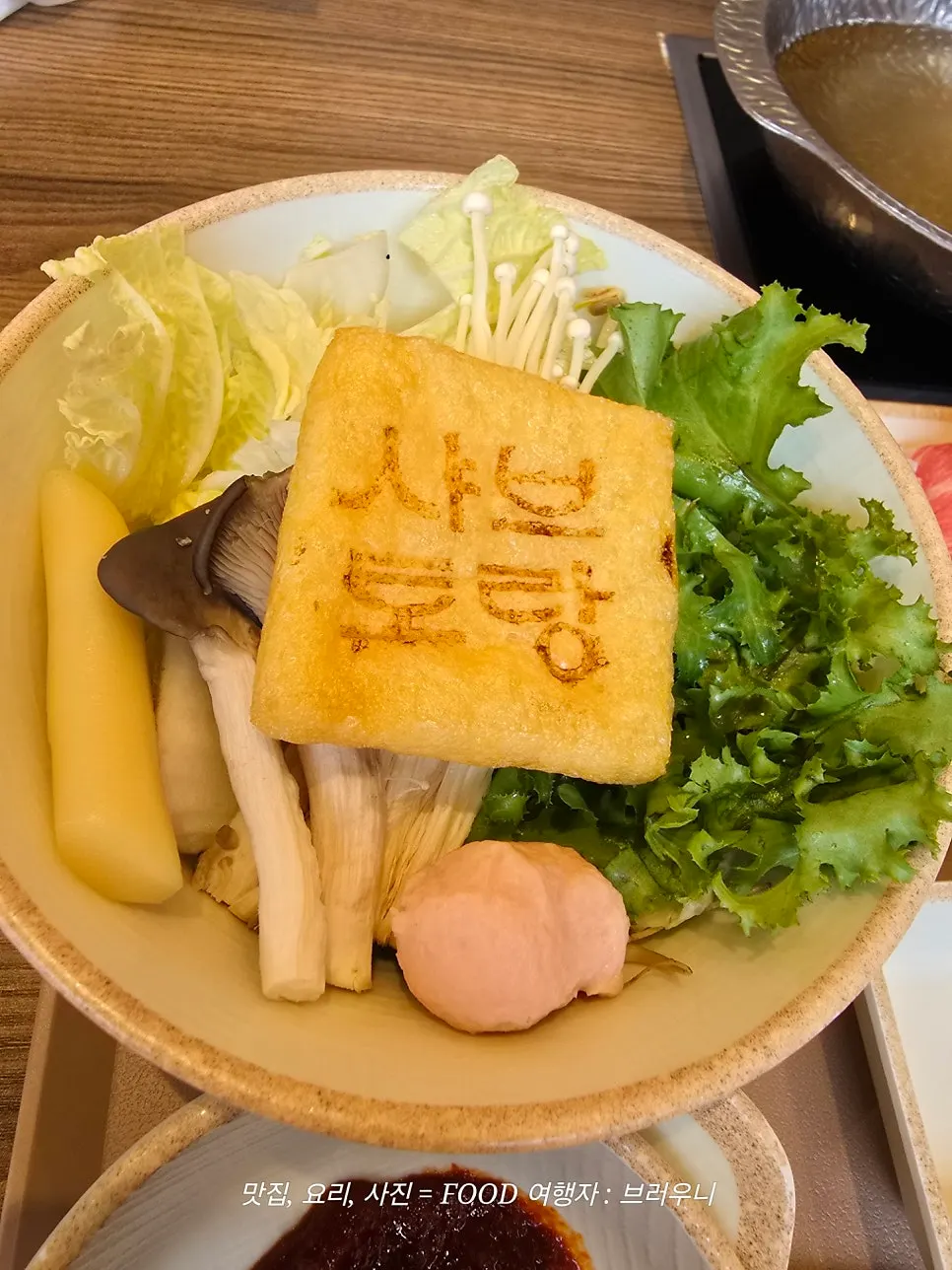 Individual pot with shabu-shabu broth and a plate of vegetables