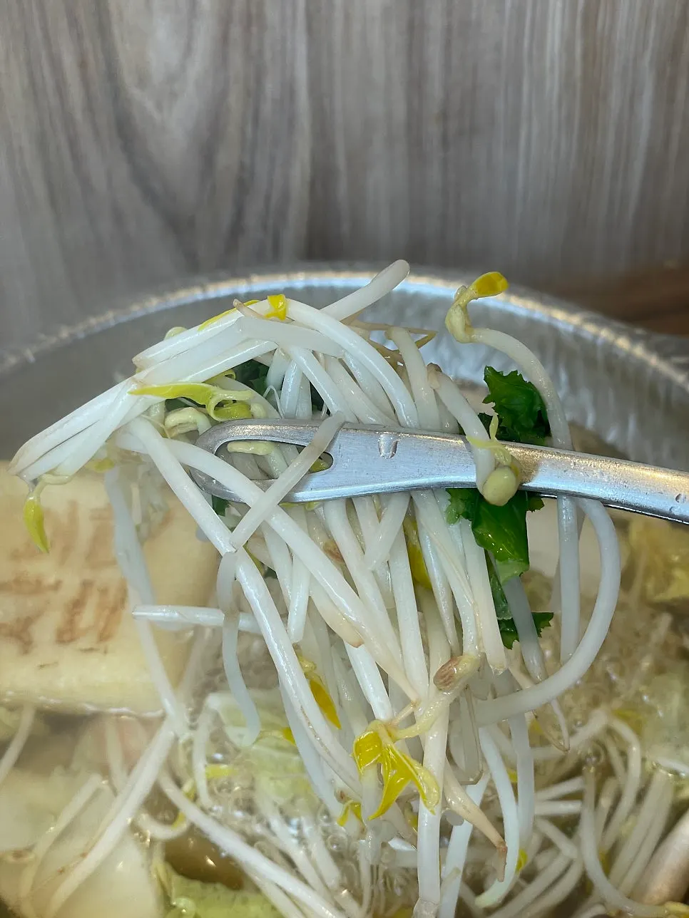 Vegetables being added to the boiling individual hot pot