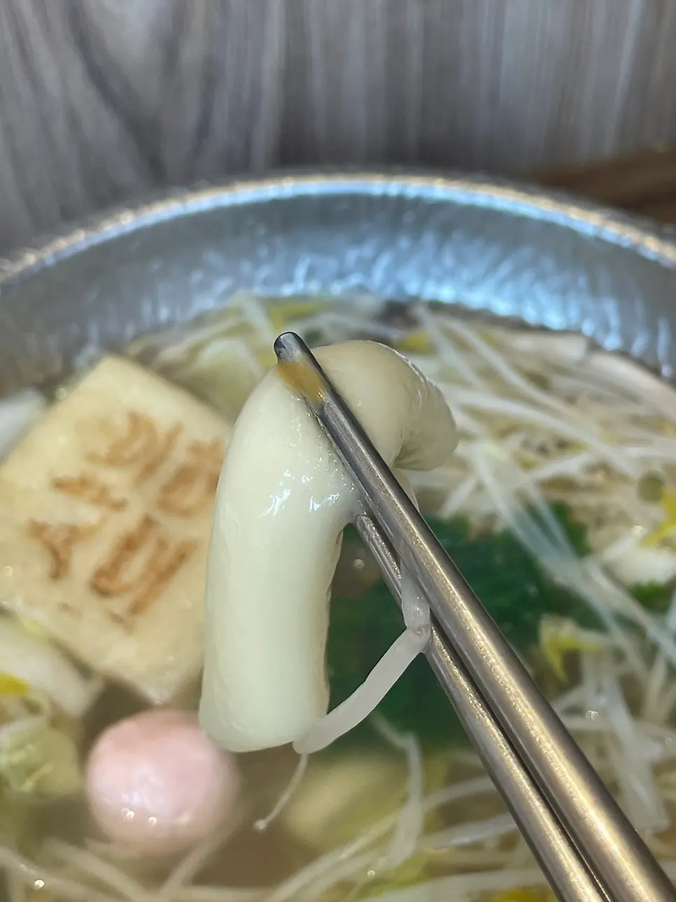 A chopstickful of bean sprouts and vegetables dipped in sauce
