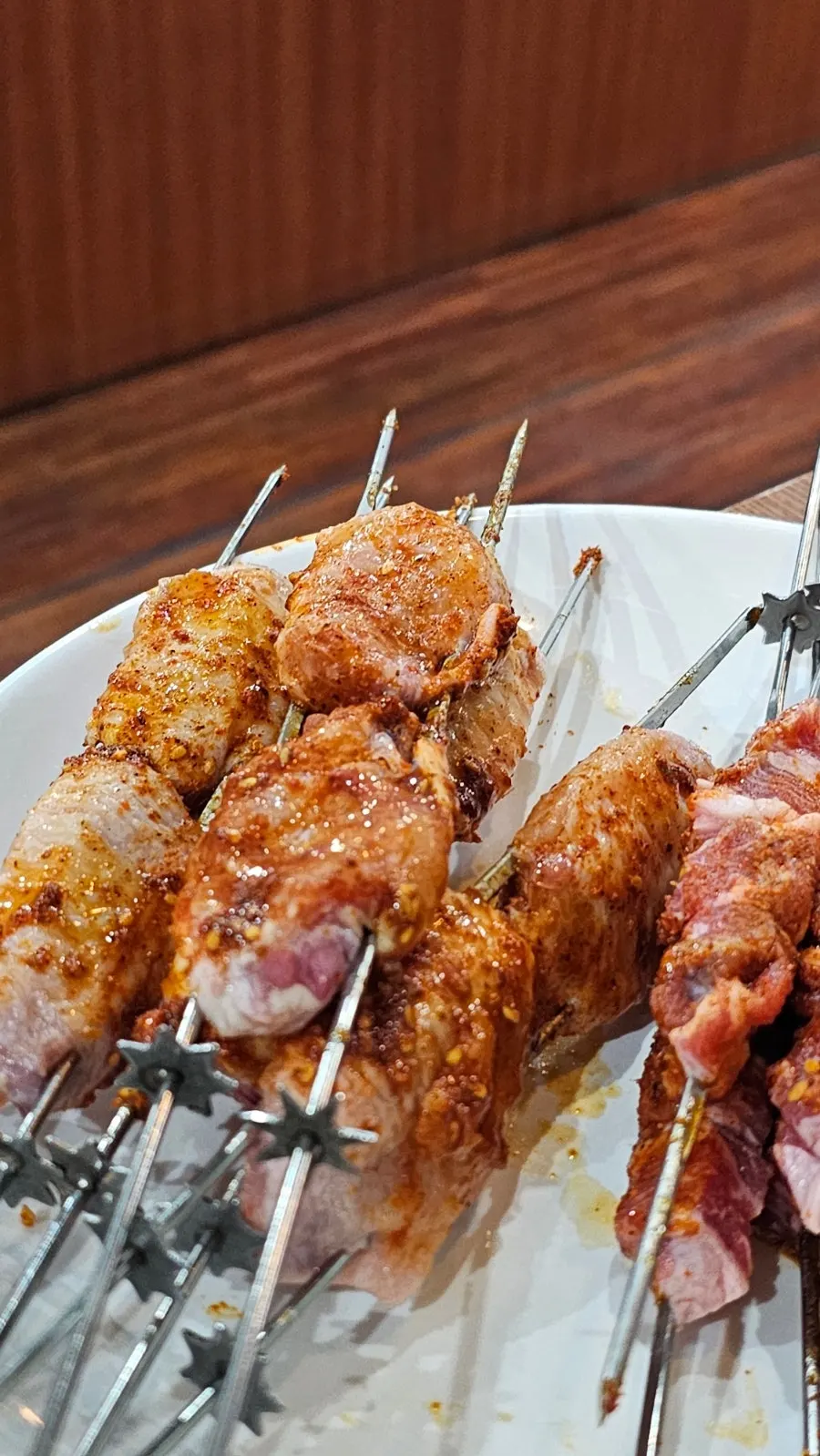 Table spread of lamb skewers, chicken wing skewers, and onmyeon