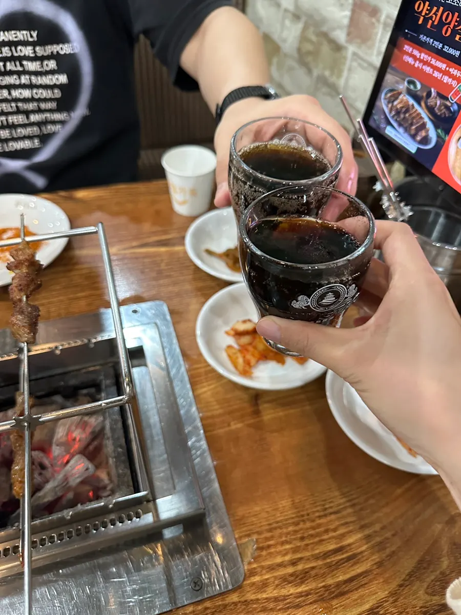 A table of lamb skewers enjoyed with cola