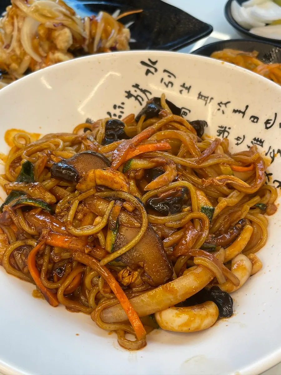 Table setting with japchaebap and stir-fried jjamppong side by side