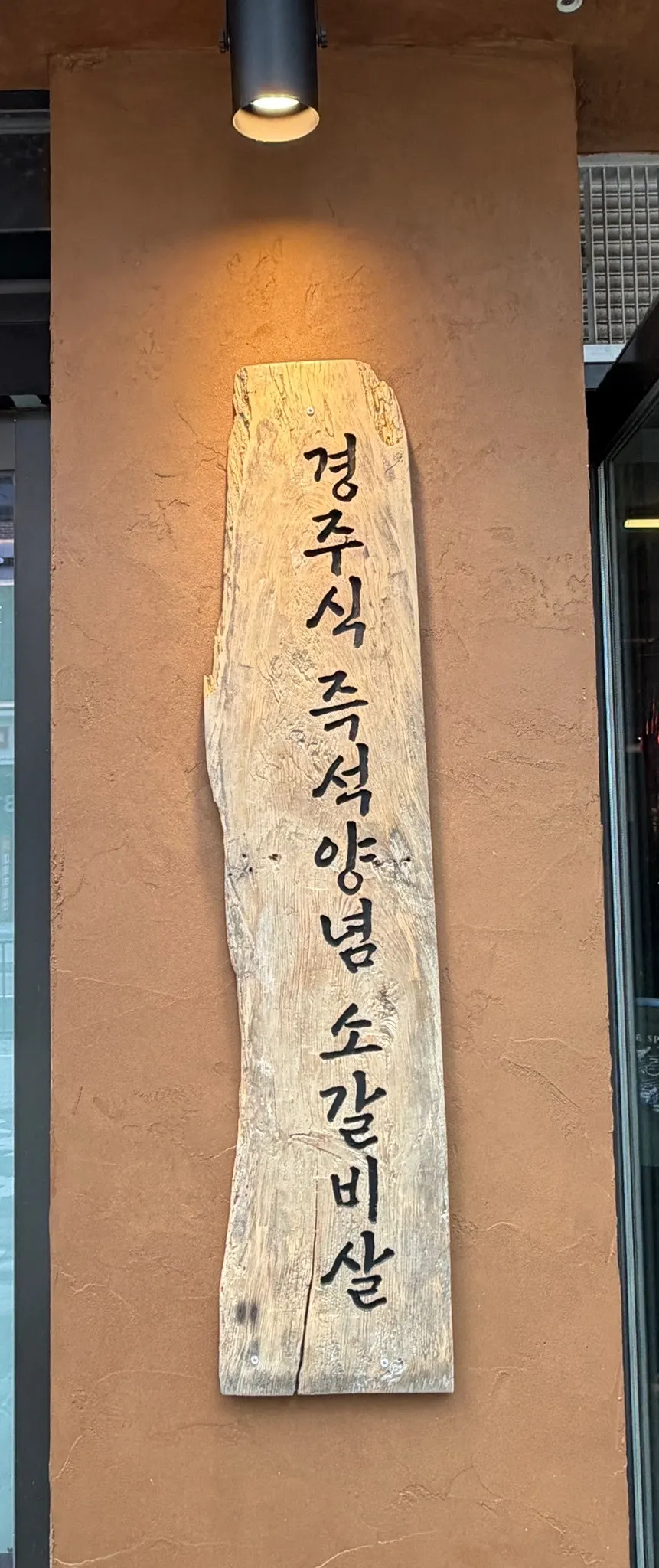 Vertical image of beef rib grilling over charcoal at Daehwa Sutbul Garden Siheung Janggok Branch
