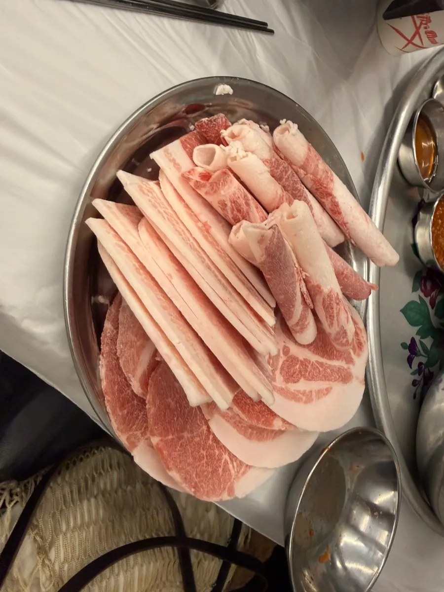 Bright red mixed platter of pork belly, pork shoulder, and brisket