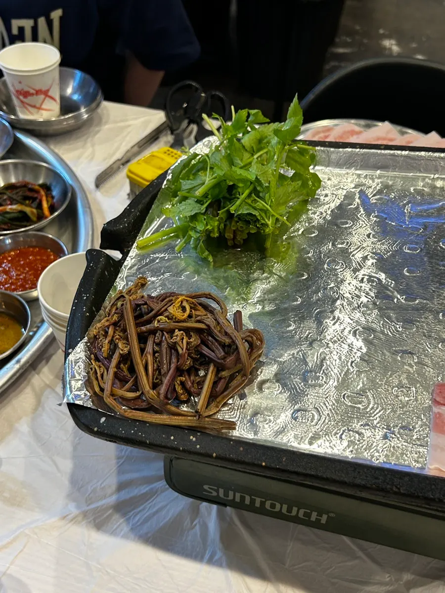 Frozen samgyeopsal and flower pork neck on the foil-covered grill