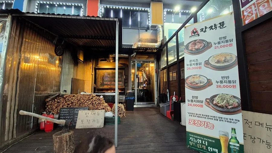 Stacked firewood and the wood-fire chicken roasting area inside the store
