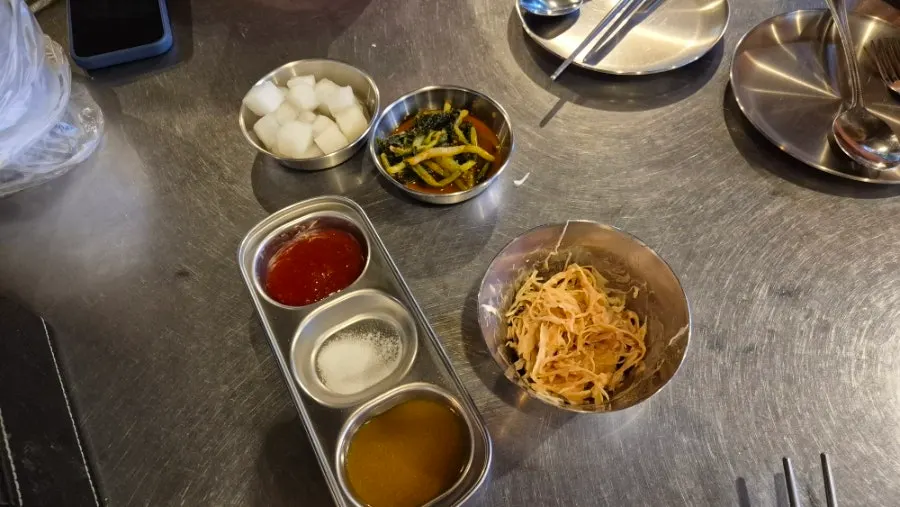 Self-serve bar with shredded cabbage, yeolmu kimchi, and pickled radish