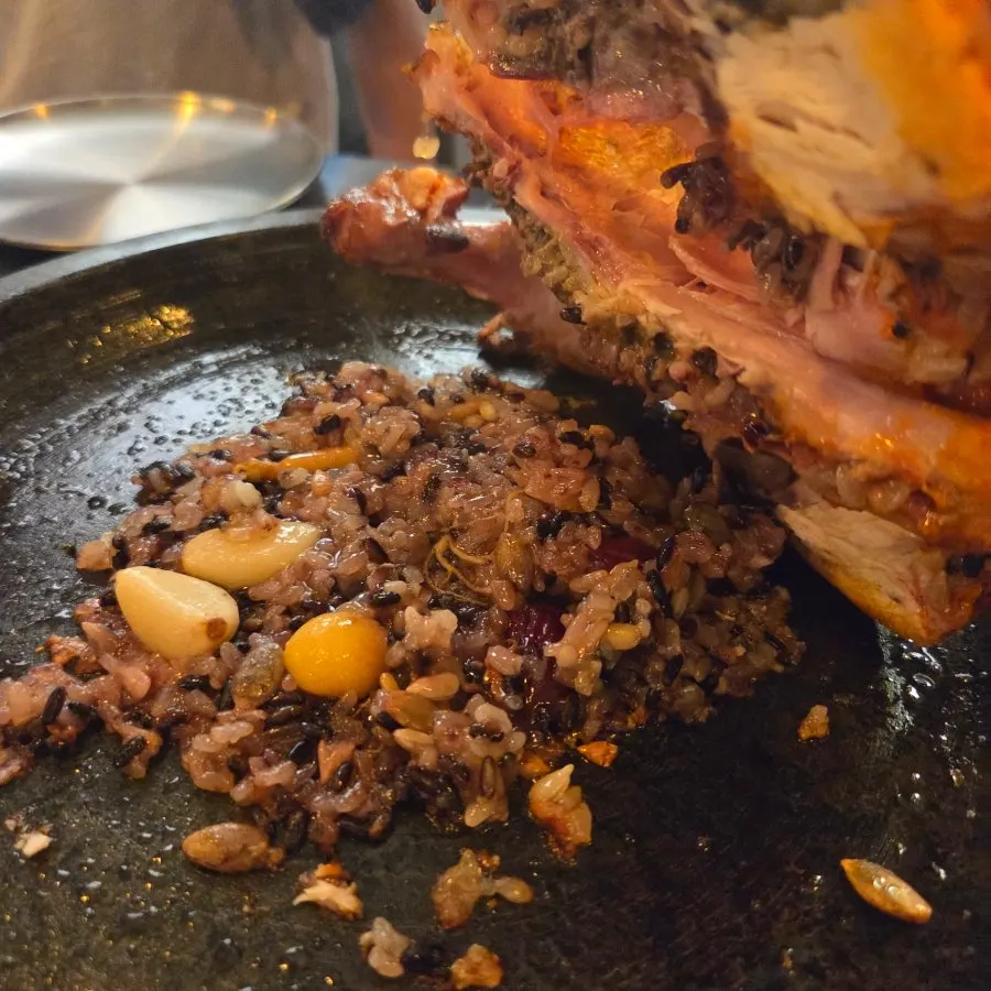 Whole chicken laid over chewy scorched rice