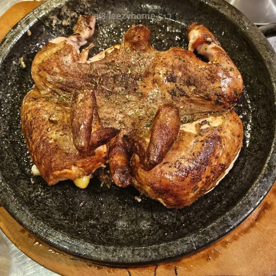 Two sizzling whole chickens on stone plates