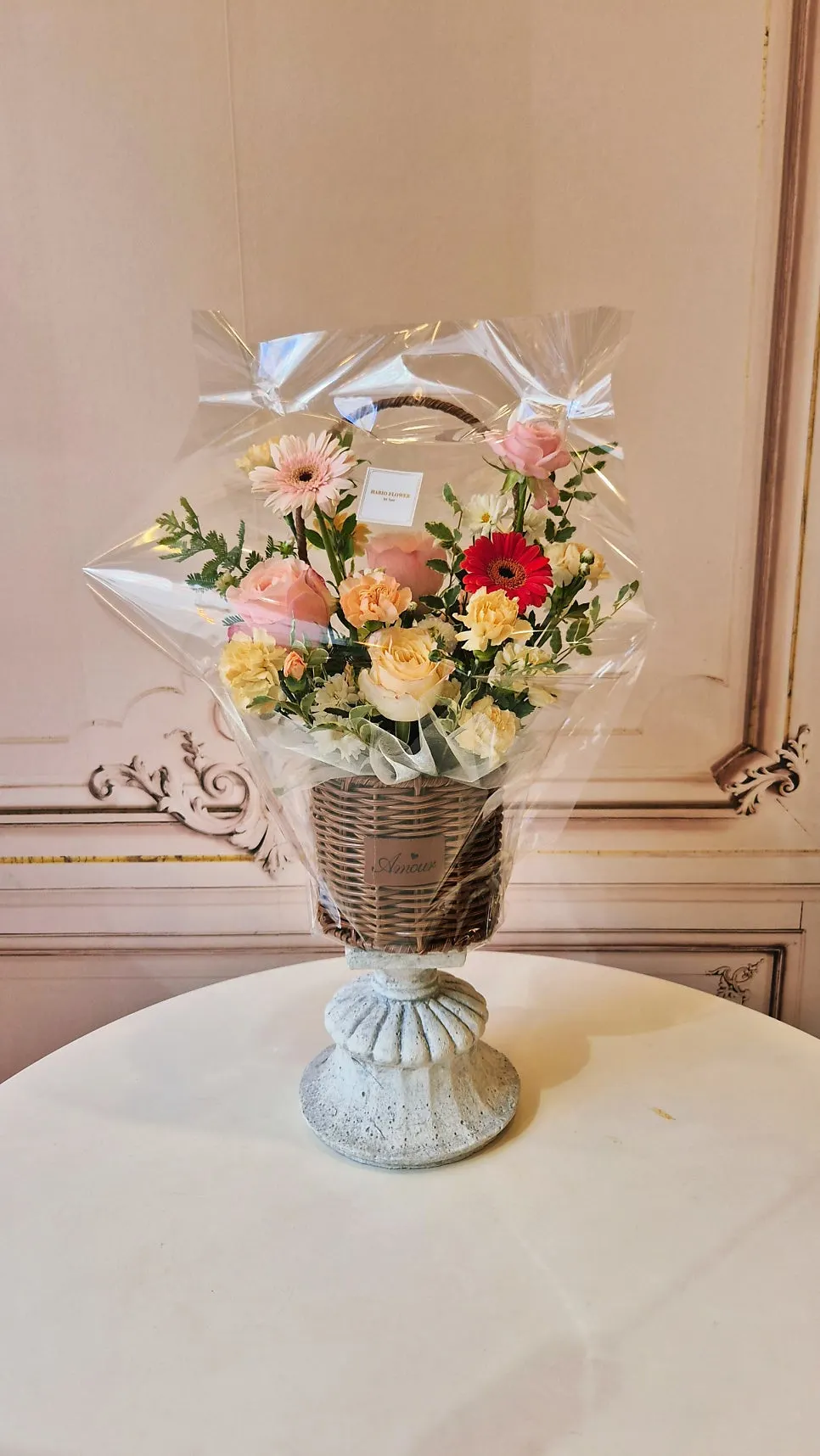 Brown flower basket in pink and peach tones with a red flower accent