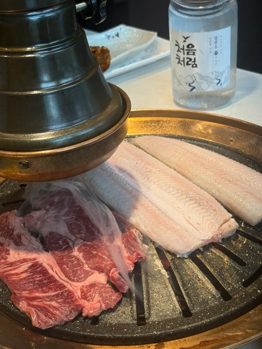 Eel and beef sirloin grilling together on the grate