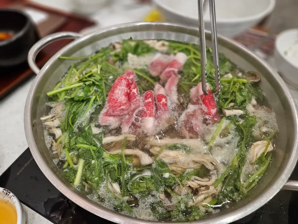 Wrapping chadol in fresh minari and dipping it in sesame oil sauce