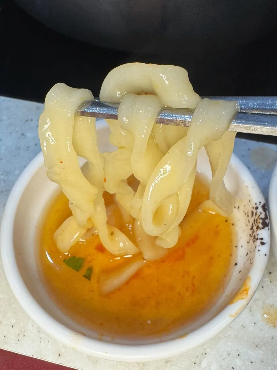 在辣汤底中煮着的自制面刀切面