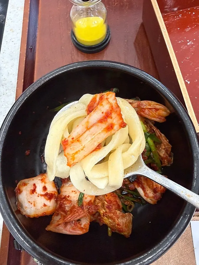 House-made kalguksu noodles stretching as they're lifted