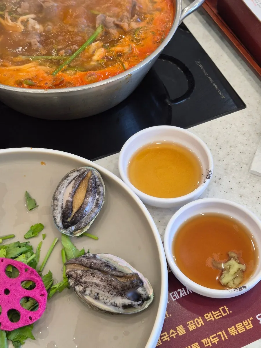 Live abalone dipped into red shabu broth