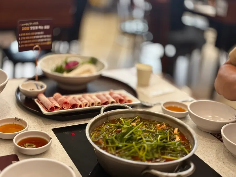 Plate of cooked vegetables and meat lifted out of the shabu kalguksu
