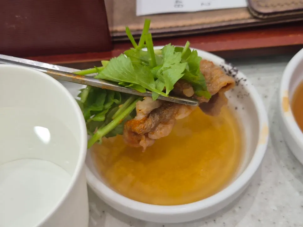 Dipping meat and minari into the sesame oil sauce