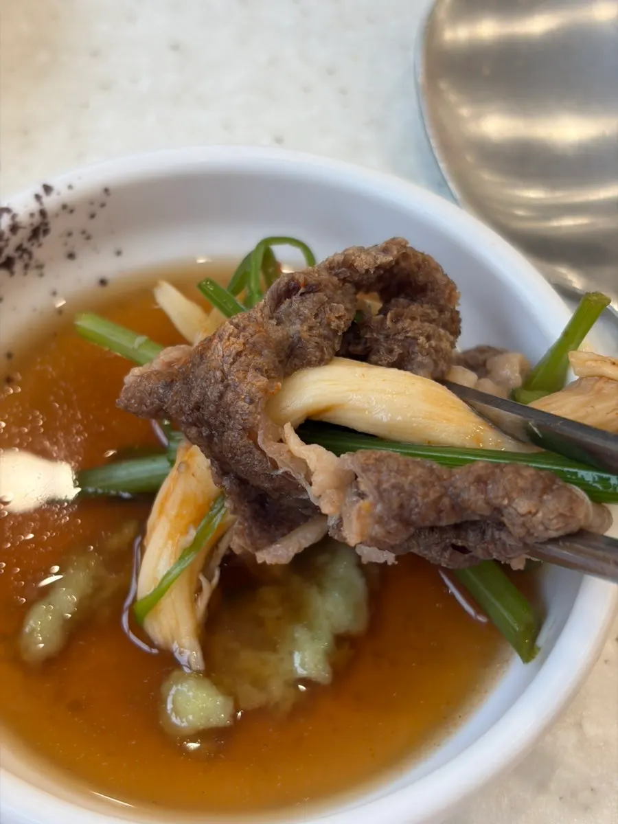 A minari wrap dipped in sesame oil sauce
