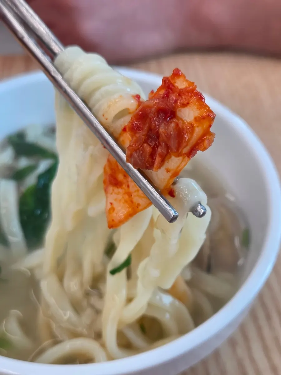 칼국수 면 위에 올린 김치 한 점