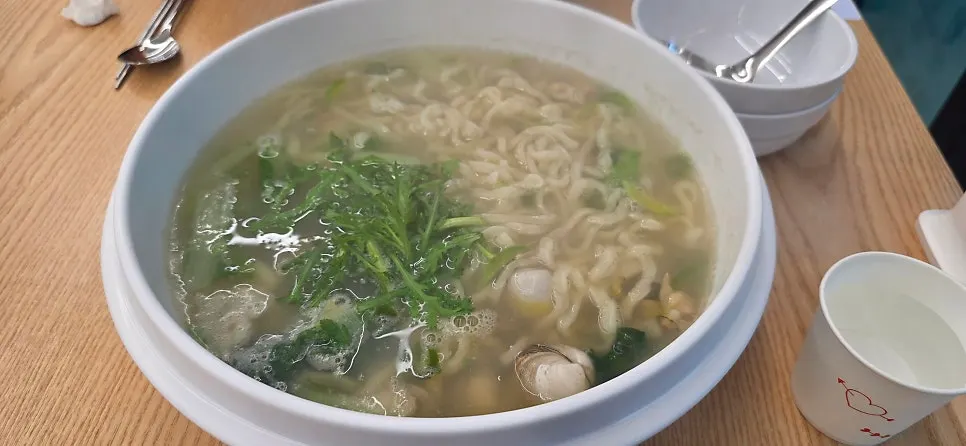 A bowl of kalguksu piled high with dongjuk clams