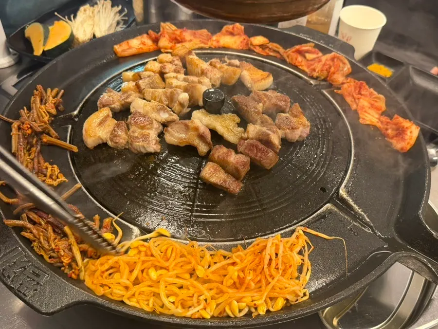 솥뚜껑 가장자리에 올린 김치와 콩나물, 고사리