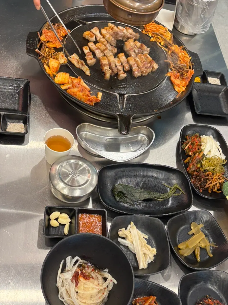 솥뚜껑에서 구워지는 야채와 삼겹살