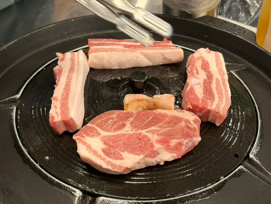 Raw pork belly and pork neck placed on the iron lid
