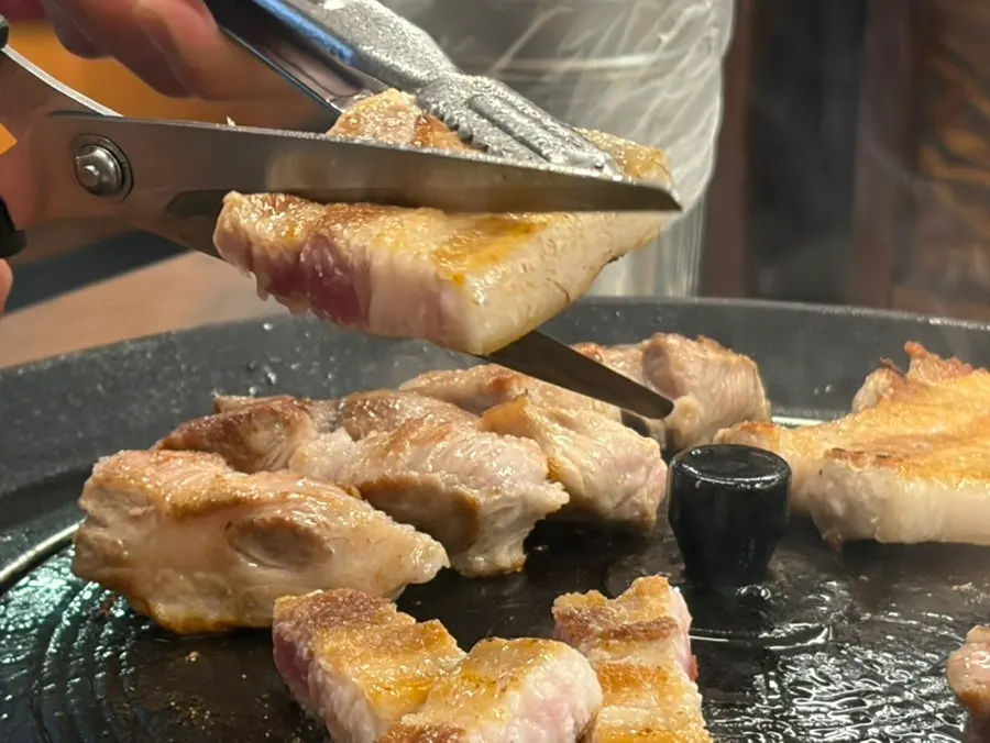 Staff grilling meat on the iron lid