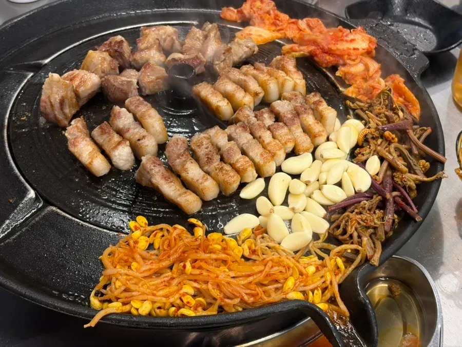 Kimchi and bean sprouts grilled at the edge of the iron lid