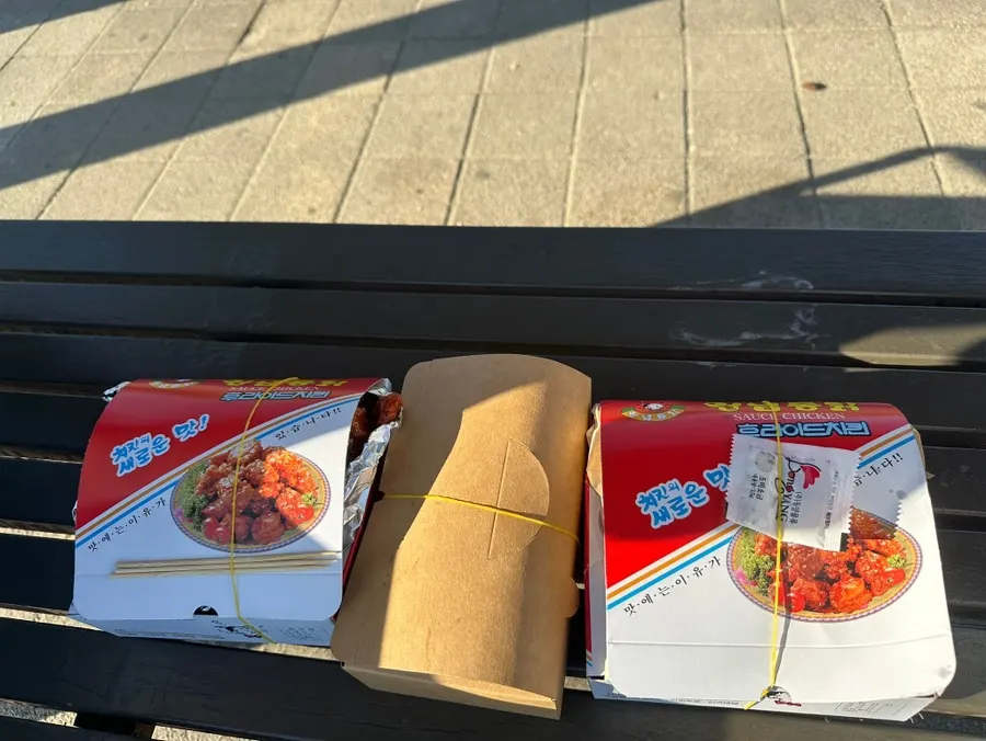 Dakgangjeong being tossed with sauce over boneless fried chicken