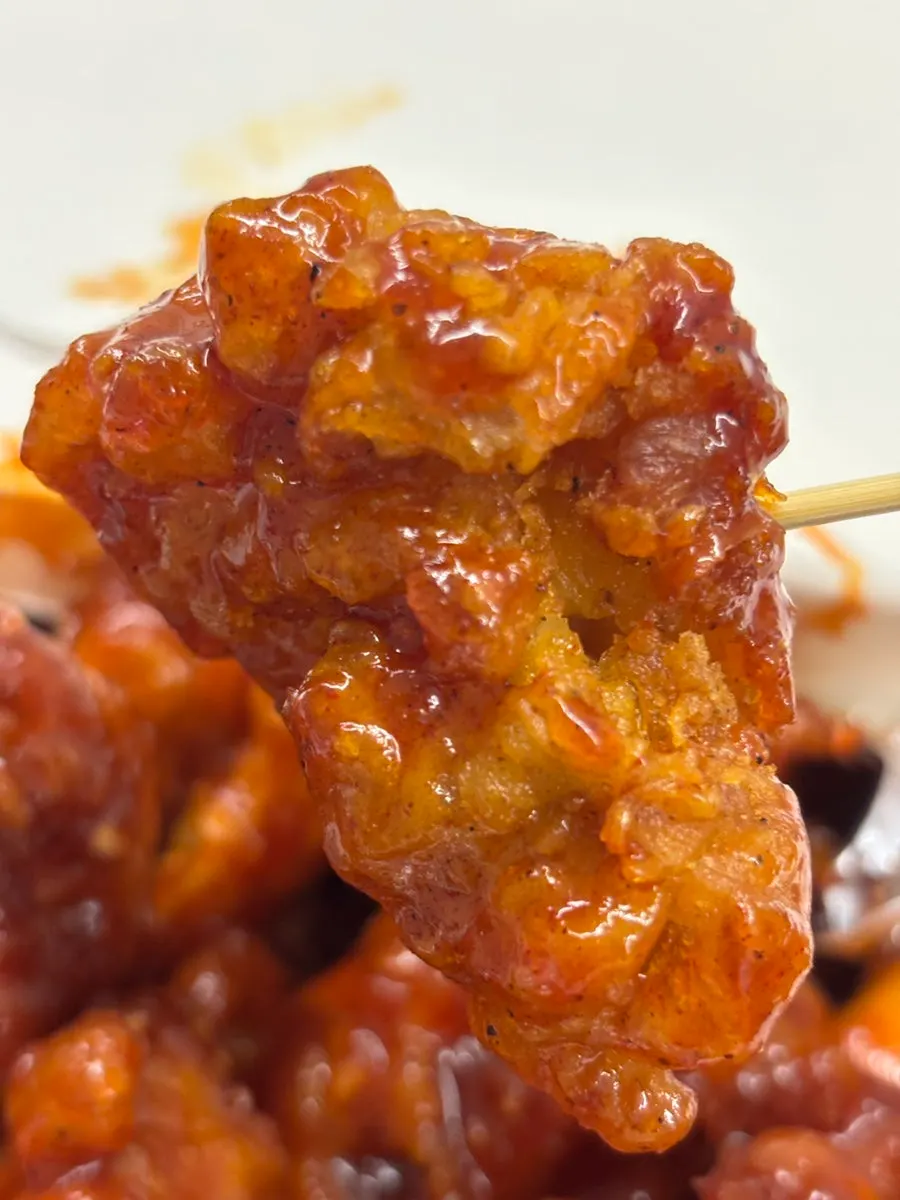 Piece of dakgangjeong coated in mild sauce