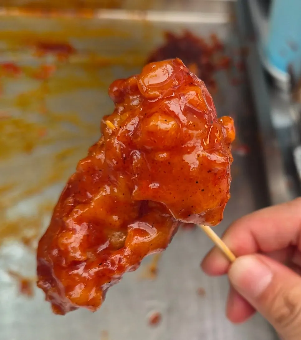 A freshly fried piece of chicken handed to a waiting customer