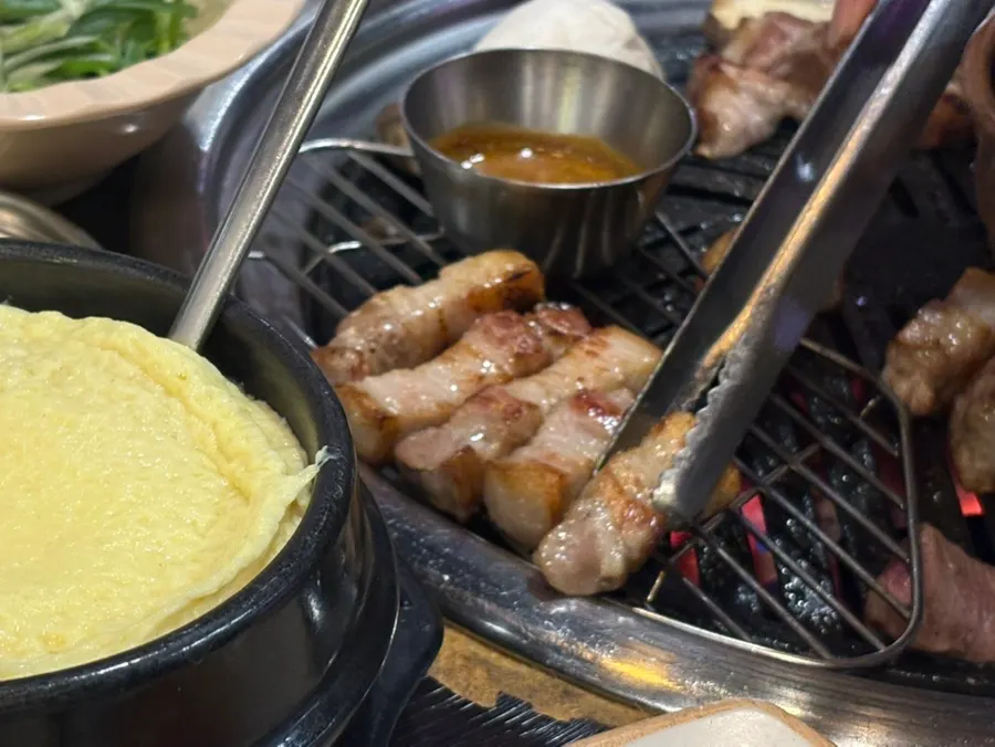 Meat grilled over charcoal by a staff member