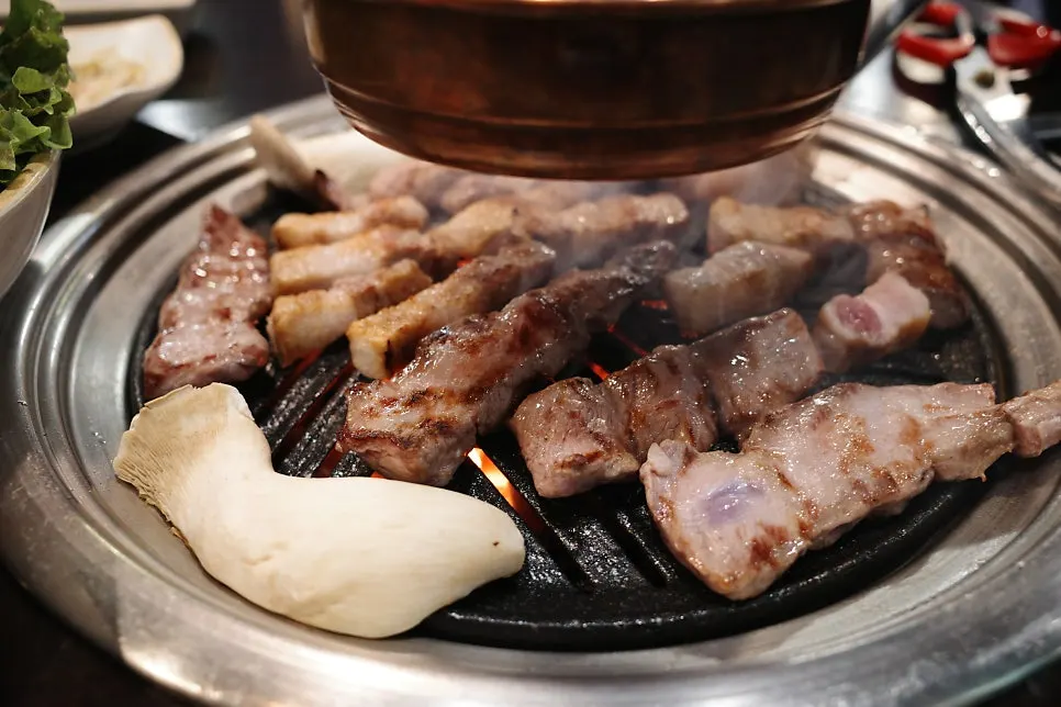 Pork belly and skirt steak cooking on the grill