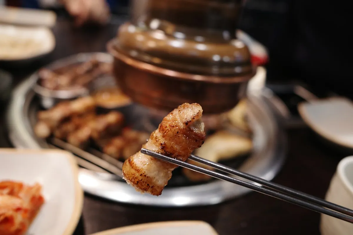 A bite of charcoal-grilled pork belly dipped in saeujeot