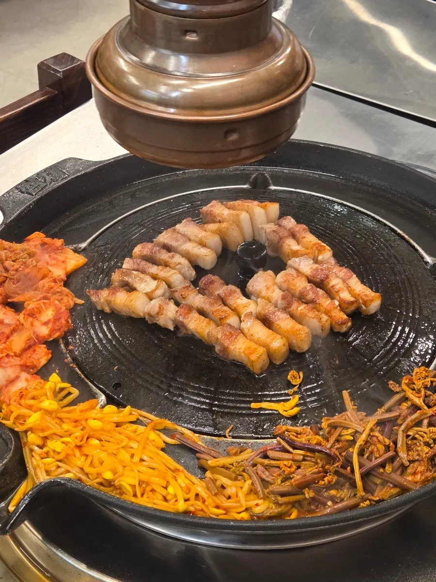 Pork belly grilling on a pot lid