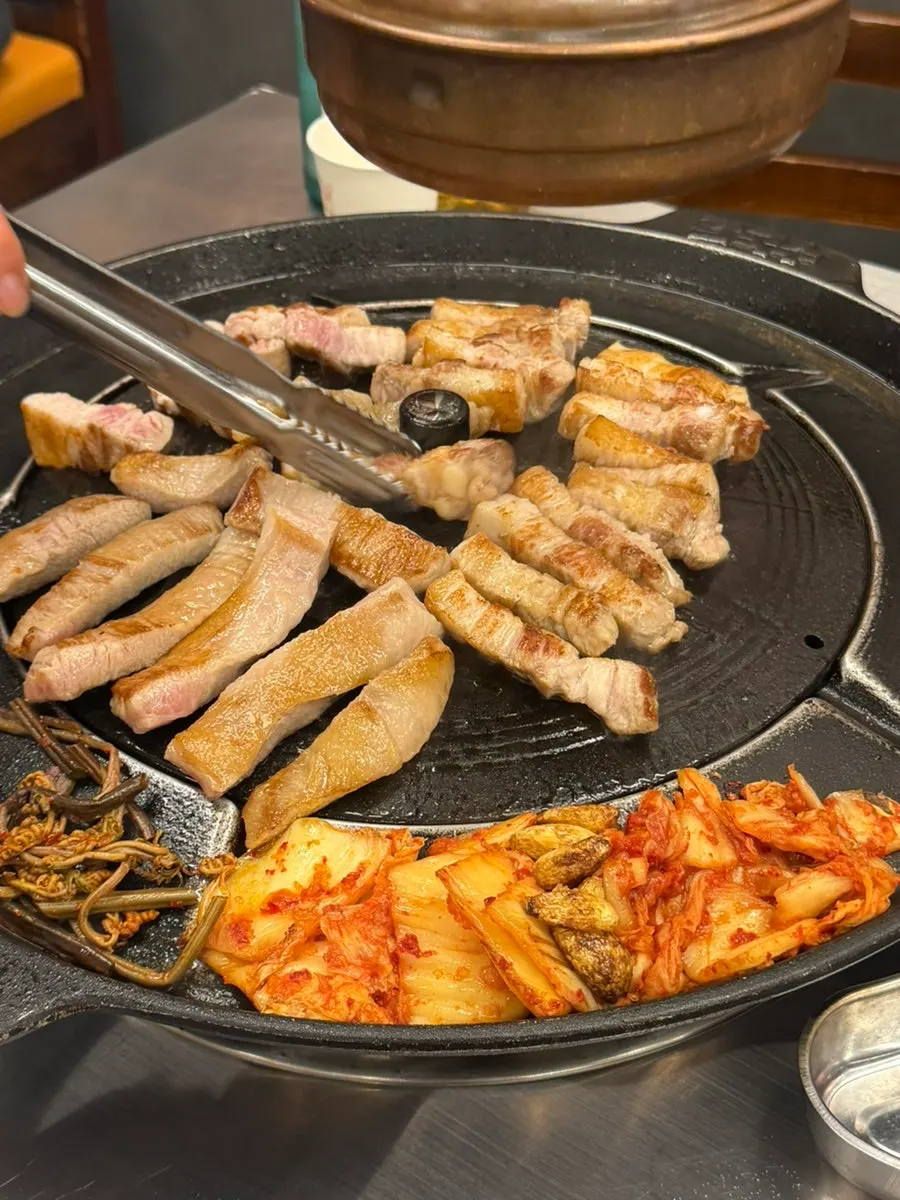 Meat grilling on a cauldron-lid grill