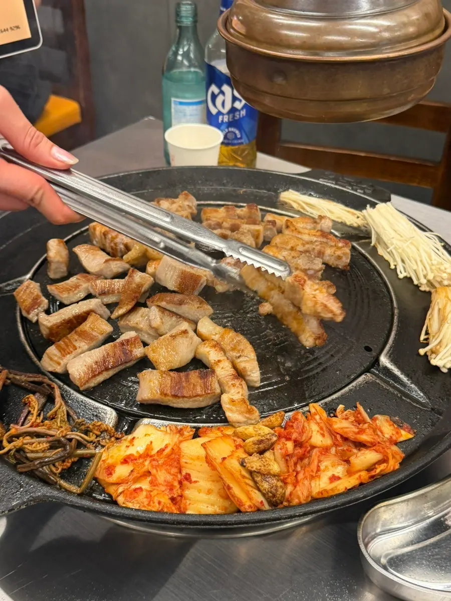 Staff grilling pork belly with accompaniments