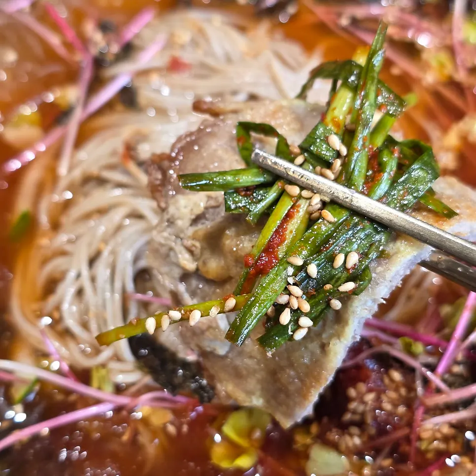 Dipping yukjeon in the broth to eat with the noodles
