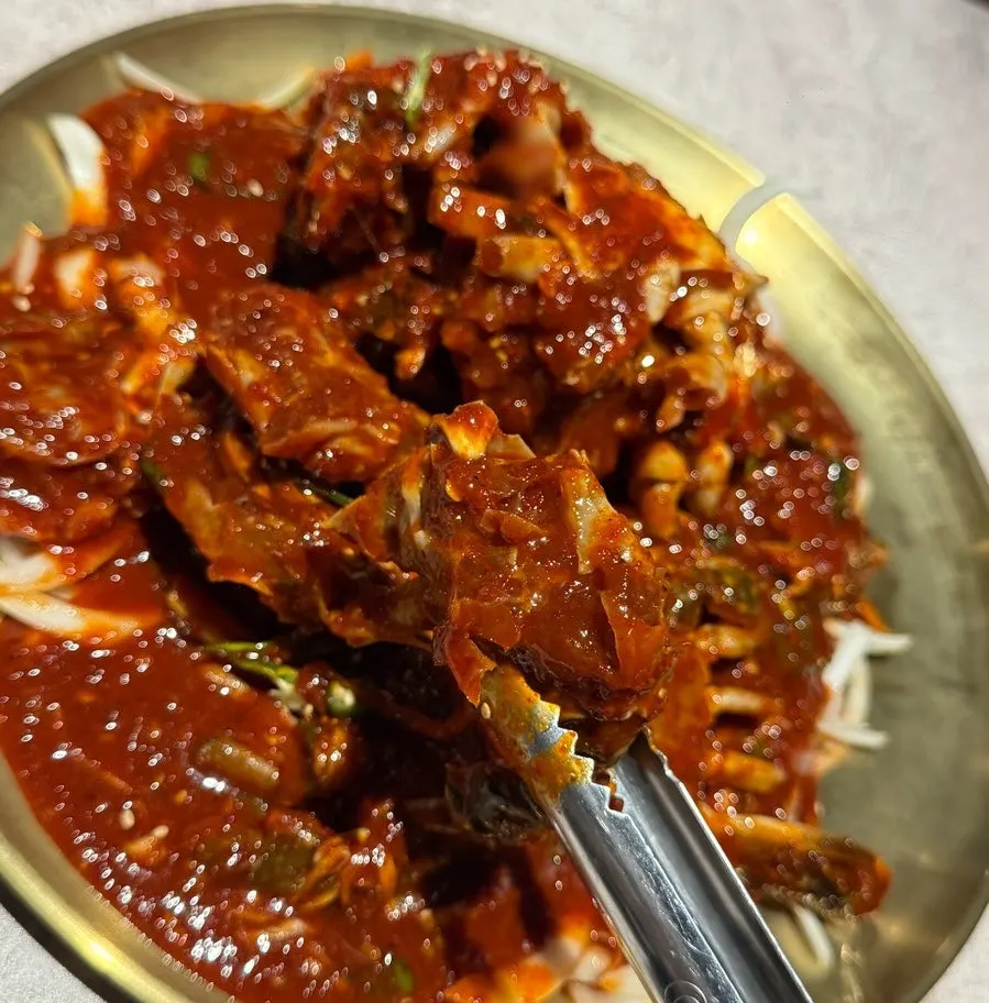 Picking up a piece of the spicy marinated crab